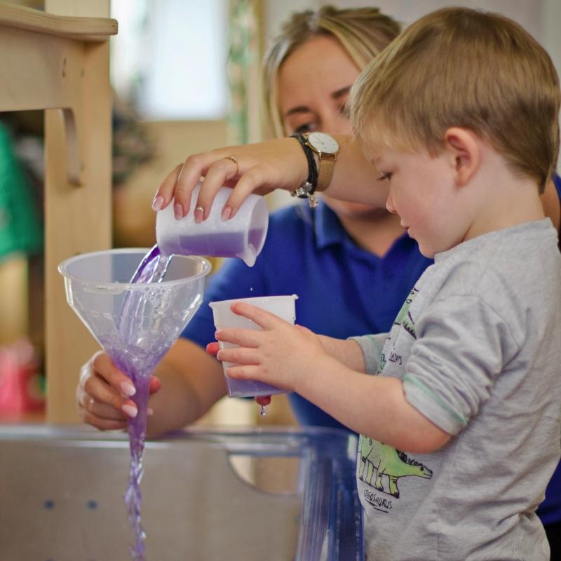 Toddler learning and playing with water funnels